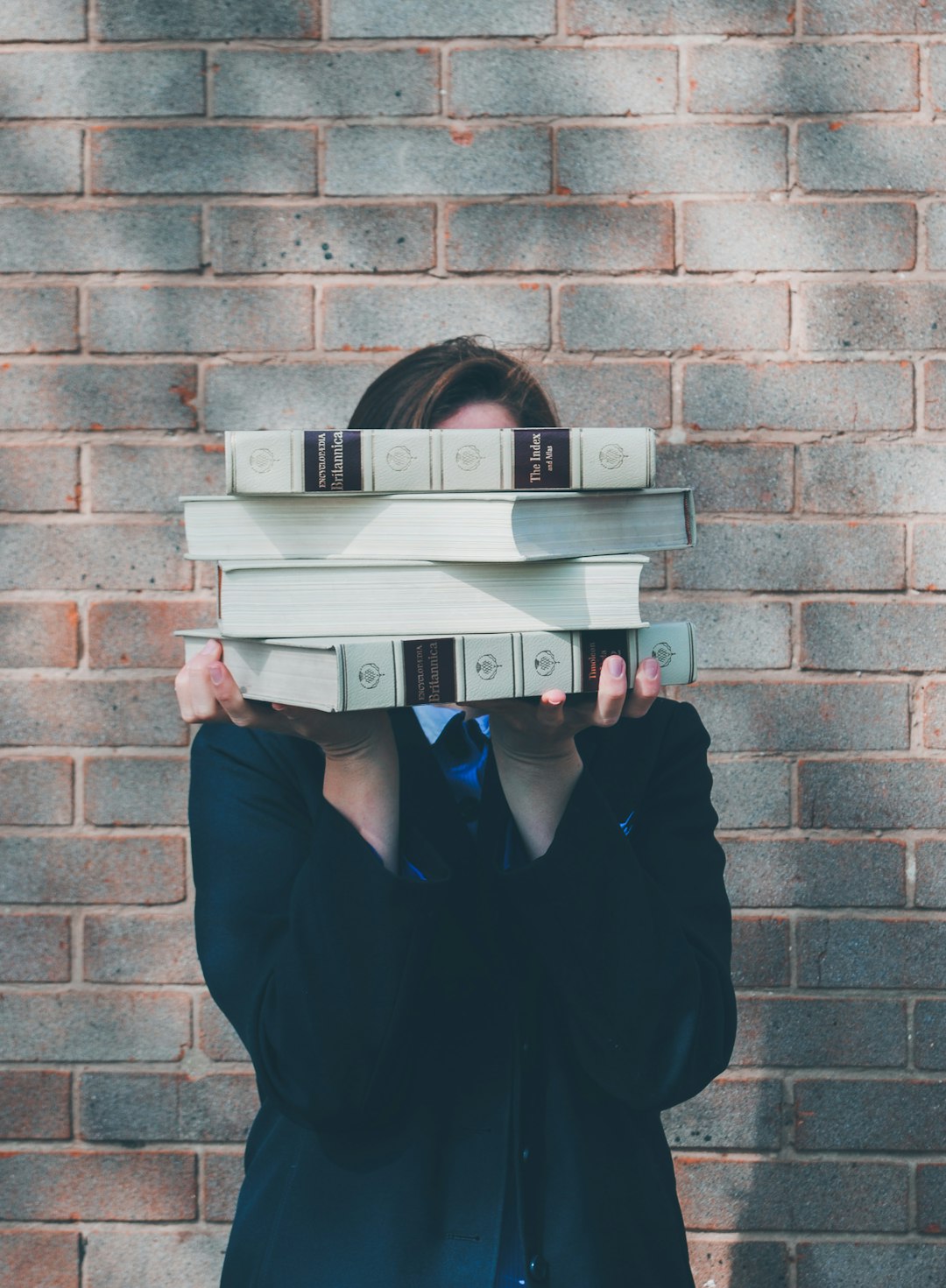 person-holding-pile-of-books-near-face-zslfoaqzeru